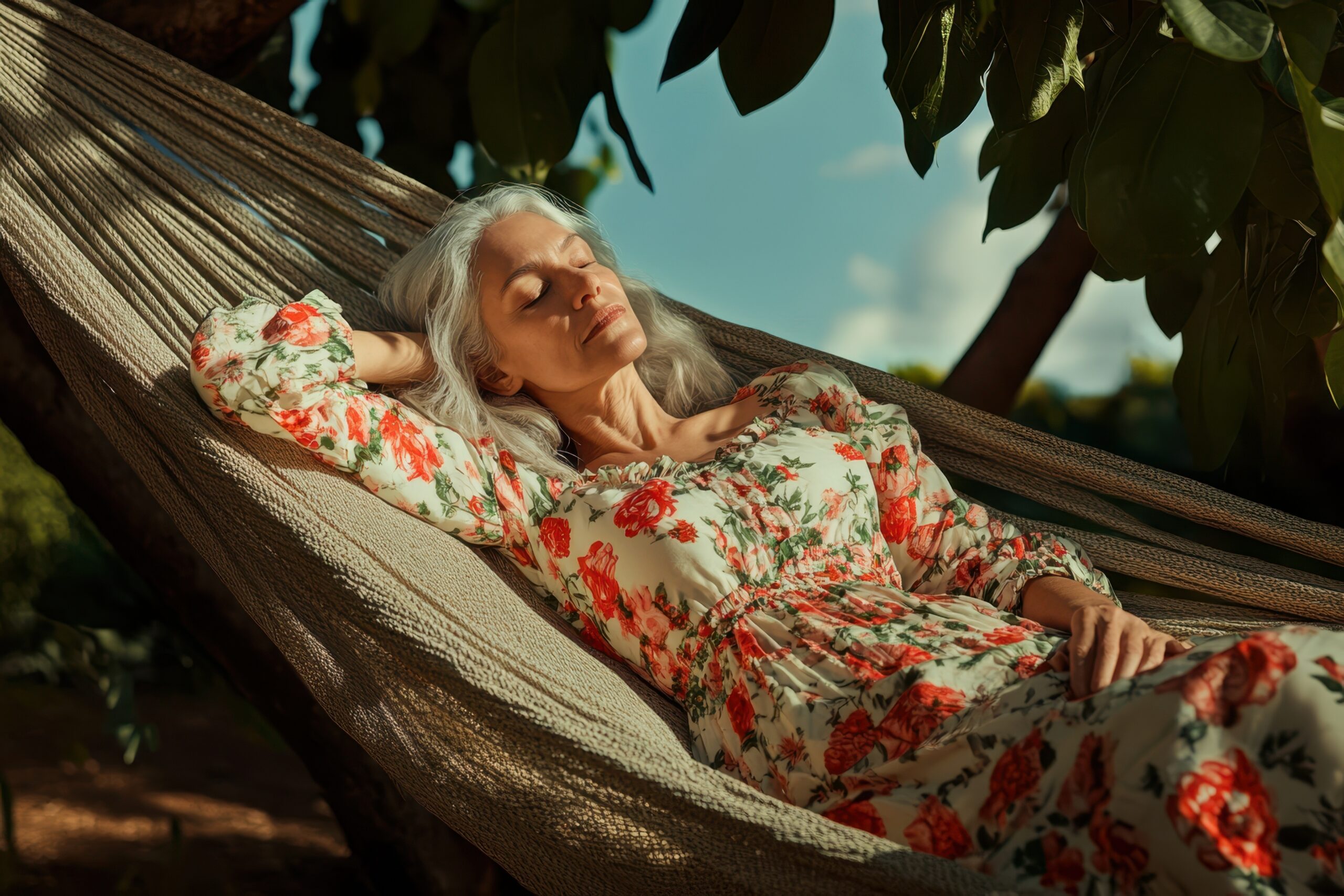 Woman in a sun dress laying in hammock peacefully with eyes closed