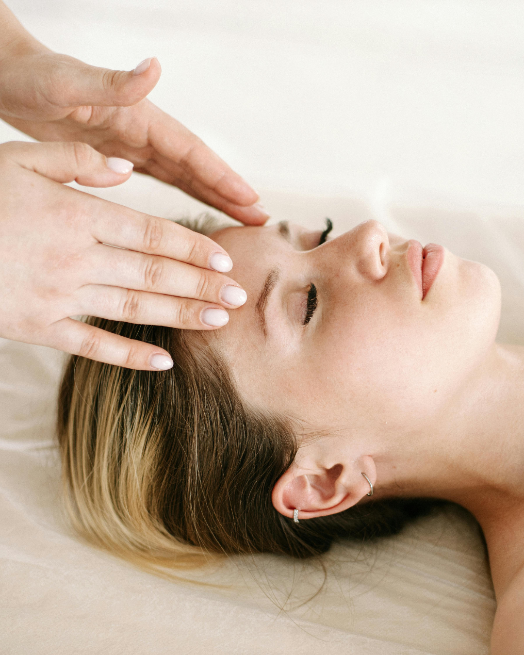 Woman receiving a healing session with grounding practices, aromatherapy, gentle facial lymphatic massage, Earth Genesis Z infrared wellness technology, Reiki energy healing, sound healing, and scalp massage